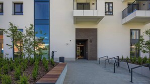 Un edificio moderno con un patio, una banca de madera y una barandilla metálica.