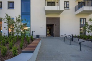 Un edificio moderno con un patio, una banca de madera y una barandilla metálica.
