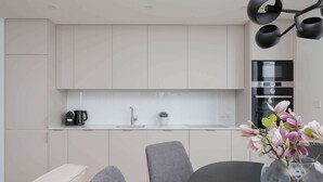 Una cocina moderna con horno integrado, cafetera y una planta en maceta sobre la encimera.