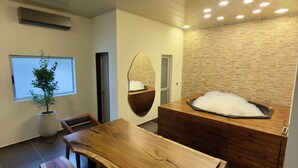 A modern interior with a wooden dining table, benches, a stone wall, and a hot tub. - An Experience of Luxury and Comfort (Medellín)