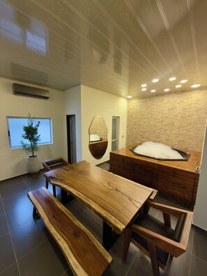 Ein modernes Interieur mit einem Holztisch, Bänken, einer Steinsäule und einer Whirlwanne.