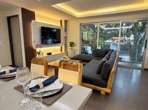 A modern living room with a sofa, dining table, and a TV mounted on the wall. - An Experience of Luxury and Comfort (Medellín)