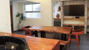 A modern kitchen with a built-in TV, a dining area with wooden furniture, and a large window. - An Experience of Luxury and Comfort (Medellín)