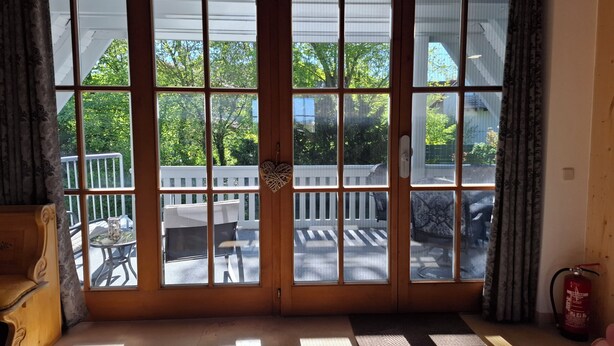 A room with a large sliding glass door leading to an outdoor deck with a white railing and a table. - Park-Studio Franconian Lake District (Georgensgmünd)
