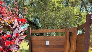 A wooden gate with a metal handle, a gravel path, and red-leafed plants. - Private Spa & Yurt with Sauna, Soaking Tub - Glamp & Walk to Main St (Murphys)