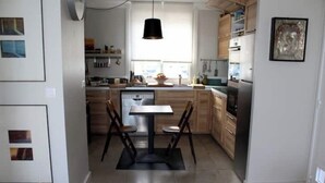 Eine moderne Küche mit Holzausstattung, einem Esstisch mit Stühlen und einer hängenden Pendelleuchte.