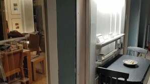 Ein Zimmer mit Esstisch, Stühlen, einem kleinen Fenster und einem Blumentopf.