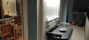 Ein Zimmer mit Esstisch, Stühlen, einem kleinen Fenster und einem Blumentopf.