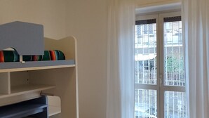 A room with a bunk bed, a ceiling fan, a window with curtains, and a view of the outside. - Eve's House. Up to 4 guests. Opposite the subway station (Roma)