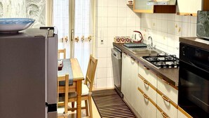 A compact kitchen with a dining area, a built-in oven, and a window with curtains. - Eve's House. Up to 4 guests. Opposite the subway station (Roma)
