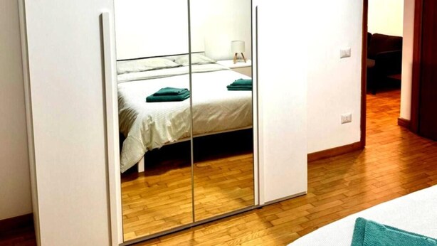 A bedroom with a large wardrobe, a bed with a white duvet, and a wooden floor. - Eve's House. Up to 4 guests. Opposite the subway station (Roma)