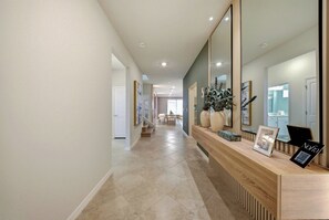 Welcome to a beautifully designed hallway featuring natural wood accents and a stylish console table with decorative vases. The serene colors and soft lighting create a warm atmosphere as you step into the heart of the home. - 10BR house sleeps 28 near Disney area (Clermont)