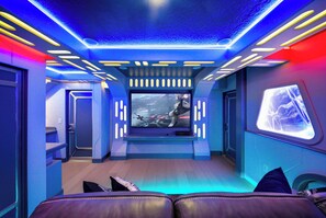Discover a stunning, futuristic living space featuring striking blue accents and vibrant lighting. Enjoy movie nights on a large screen from the sleek entertainment unit, while the plush seating invites you to relax in comfort. - 10BR house sleeps 28 near Disney area (Clermont)