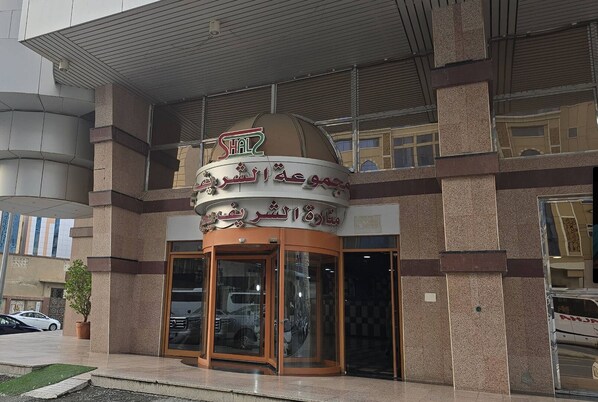 A building with a sign in Arabic, a glass entrance, and a potted plant outside. - Apartment in Makkah (Makkah)