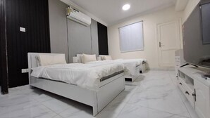 A bedroom with two beds, a TV, a wardrobe, and an air conditioning unit.
