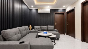 Una sala moderna con un sofá modular, una mesa de centro redonda y un equipo de aire acondicionado instalado en la pared.