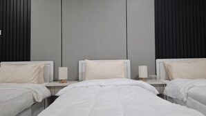 A hotel room with three beds, a grey wall, and a black panel. - Apartment in Makkah (Makkah)