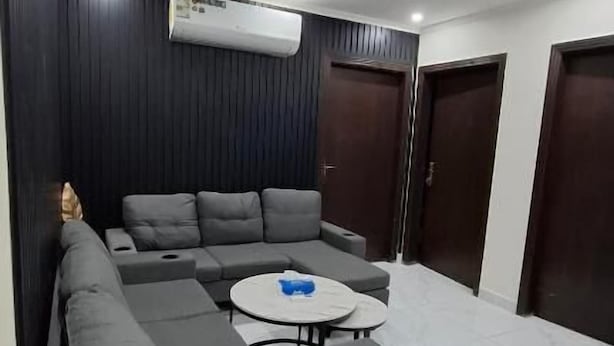 A modern living room with a sectional sofa, a round coffee table, and a built-in air conditioning unit.