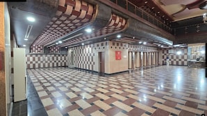A spacious lobby with a checkered floor, a fire alarm, and a staircase.