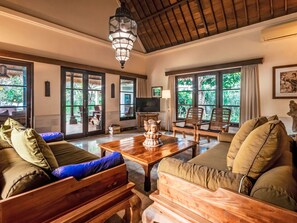 Un salón amplio con techo de madera, ventanas grandes y una mesa central con un objeto decorativo.