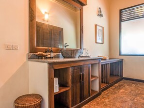 Un baño con tocador de madera, un espejo grande y una ventana.
