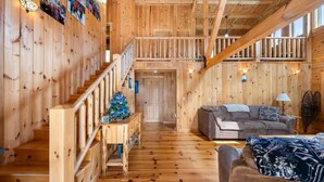 Un interior de madera con una escalera, un sofá y un árbol de Navidad.