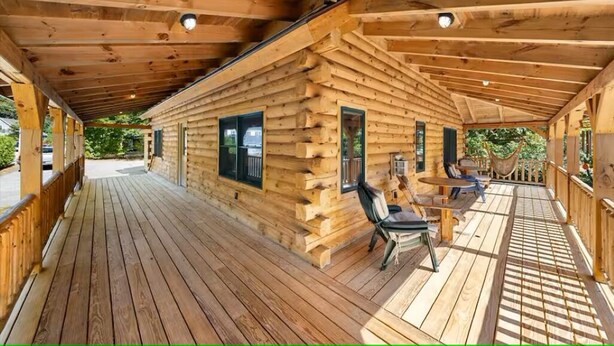 Una cabaña de madera con porche cubierto, terraza de madera y zona de estar al aire libre.