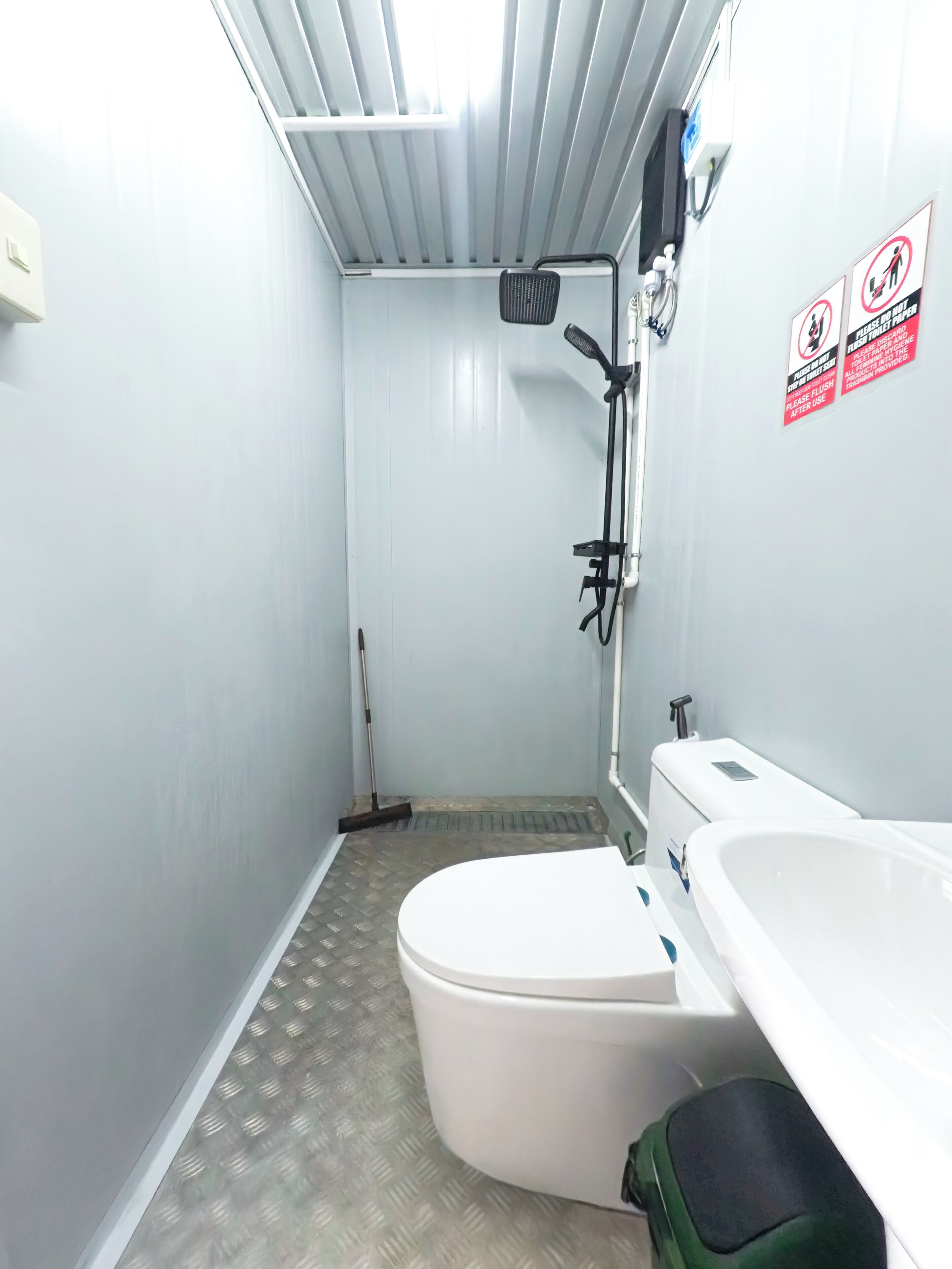 A small, compact bathroom with a toilet, a shower, and a sink.