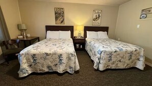 Une chambre d’hôtel avec deux lits, une table de chevet avec une lampe et une chaise.