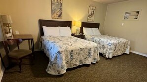Une chambre d’hôtel avec deux lits, un bureau, une chaise et une lampe.