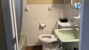 Une salle de bain équipée de toilettes, d’un lavabo et d’une poubelle.