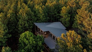 A house surrounded by dense forest with a large deck and a metal roof. - Dual Deck Hangouts/Game Loft/Hot Tub/Hochatown! (BROKEN BOW)