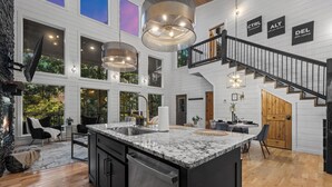 A spacious kitchen with a large island, a dining area, and a staircase leading to an upper level. - Dual Deck Hangouts/Game Loft/Hot Tub/Hochatown! (BROKEN BOW)