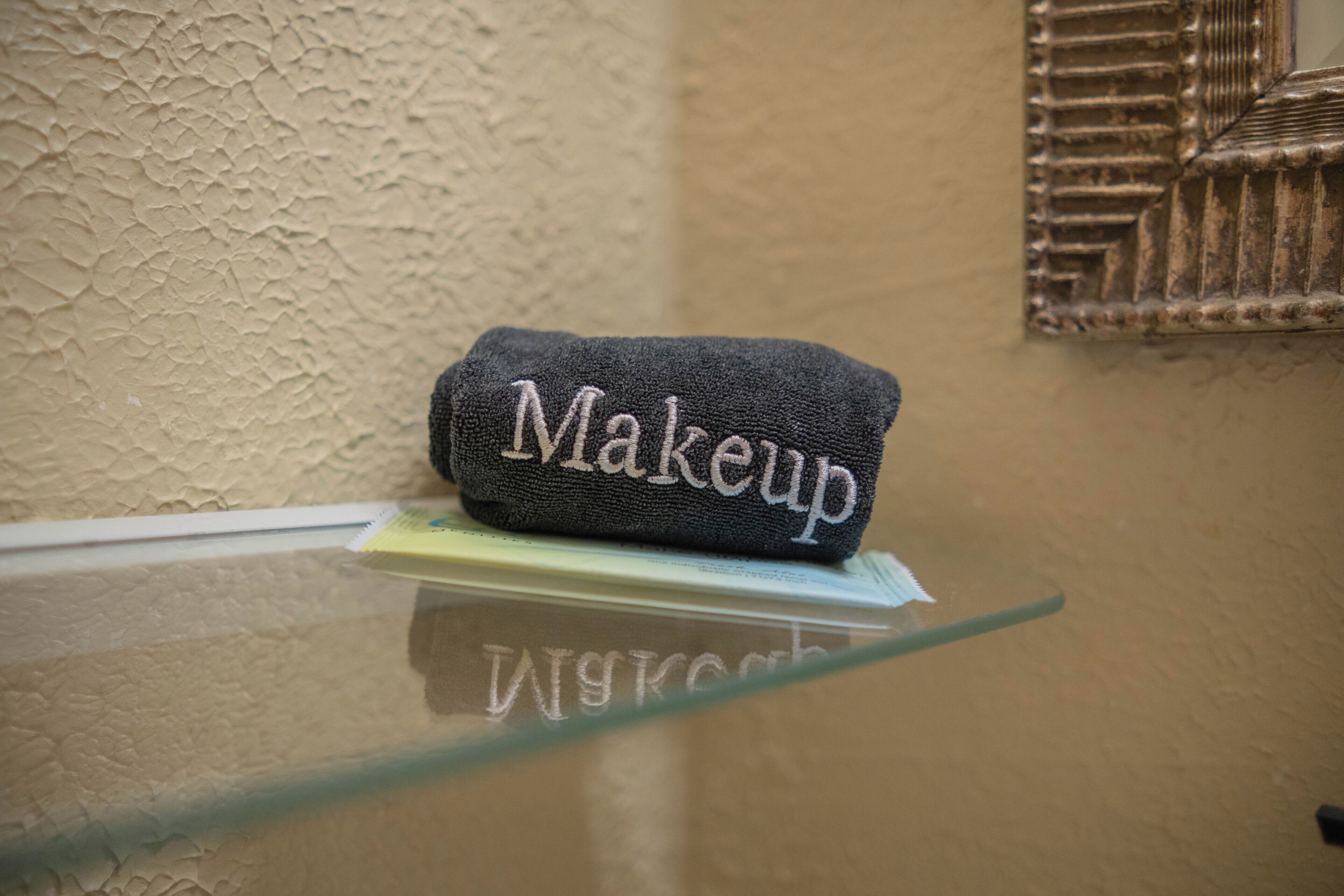 A towel with the word 'Makeup' embroidered on it, placed on a glass surface.