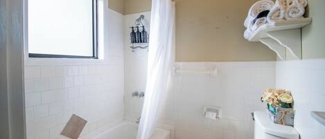 Un baño con bañera, inodoro y ventana.
