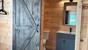 Un interior de madera con una puerta corredera, un inodoro y un lavabo con armarios.