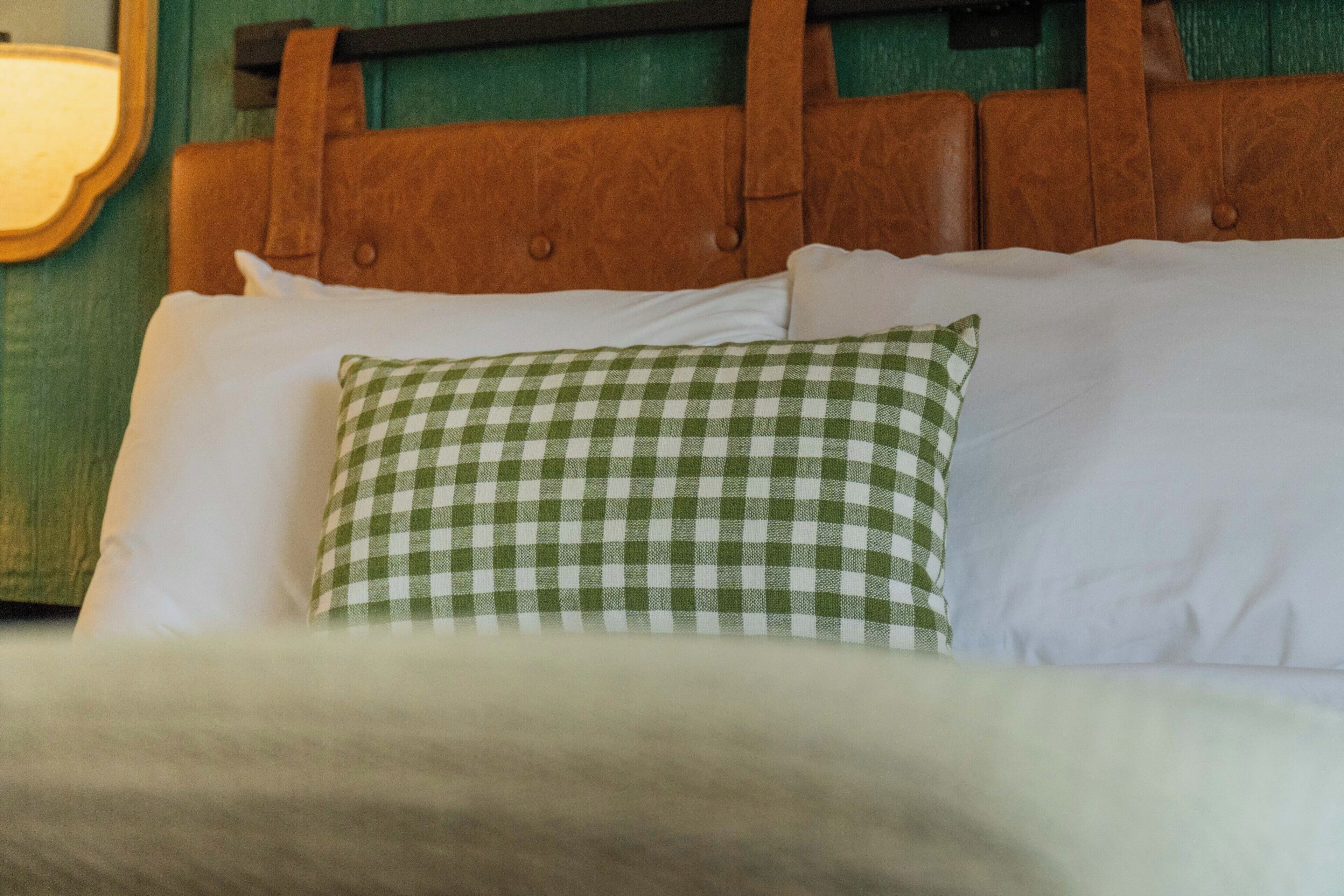 Una cama con un cojín a cuadros y un cabecero de madera.