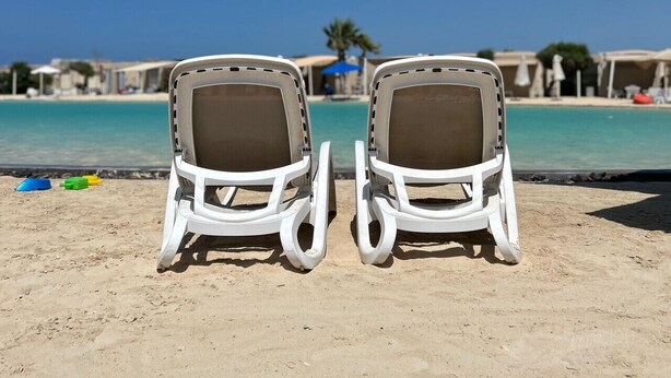 Two white lounge chairs facing a pool with a clear blue sky. - Hacienda Bay Lagoon Cabin | Beachfront Escape (Sidi abdelrahman , al Alamein)