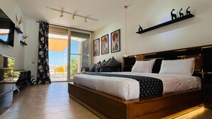 A spacious bedroom with a large bed, a TV, a ceiling light, and a view of the outdoors. - Hacienda Bay Lagoon Cabin | Beachfront Escape (Sidi abdelrahman , al Alamein)