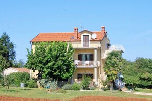 Un immeuble de deux étages doté d’un balcon, d’une antenne parabolique et d’un jardin.