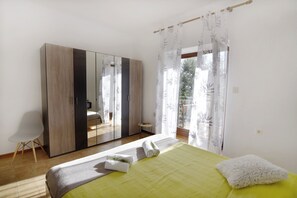 A bedroom with a bed, a wardrobe, a small table, and a balcony with curtains. - Green Retreat Near the Coast (Umag)