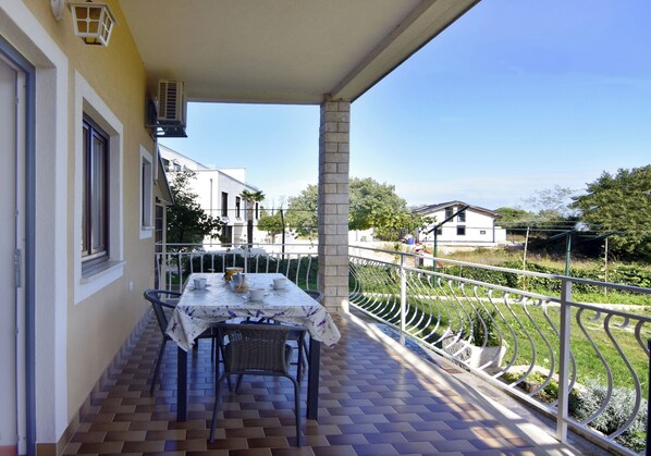 A balcony with a table and chairs, a railing, and a view of the neighborhood. - Green Retreat Near the Coast (Umag)