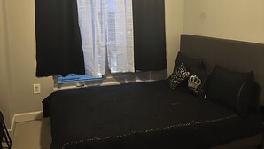 A room with a bed, a window with curtains, a wall socket, and a carpeted floor. - Cozy 2-bedroom condo with AC in lovely Atlanta Buckhead (Atlanta)