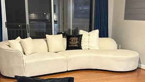 A living room with a curved sofa, a black and gold chair, and a glass door leading to a balcony. - Cozy 2-bedroom condo with AC in lovely Atlanta Buckhead (Atlanta)