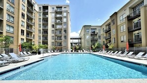 A swimming pool with lounge chairs, surrounded by multi-story buildings with balconies. - Cozy 2-bedroom condo with AC in lovely Atlanta Buckhead (Atlanta)