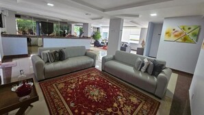 Ein modernes Wohnzimmer mit zwei Sofas, einem roten Teppich mit Muster und einer Küche im Hintergrund.