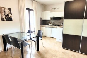 Uma cozinha moderna com armários brancos, uma mesa de jantar de vidro e cadeiras pretas.