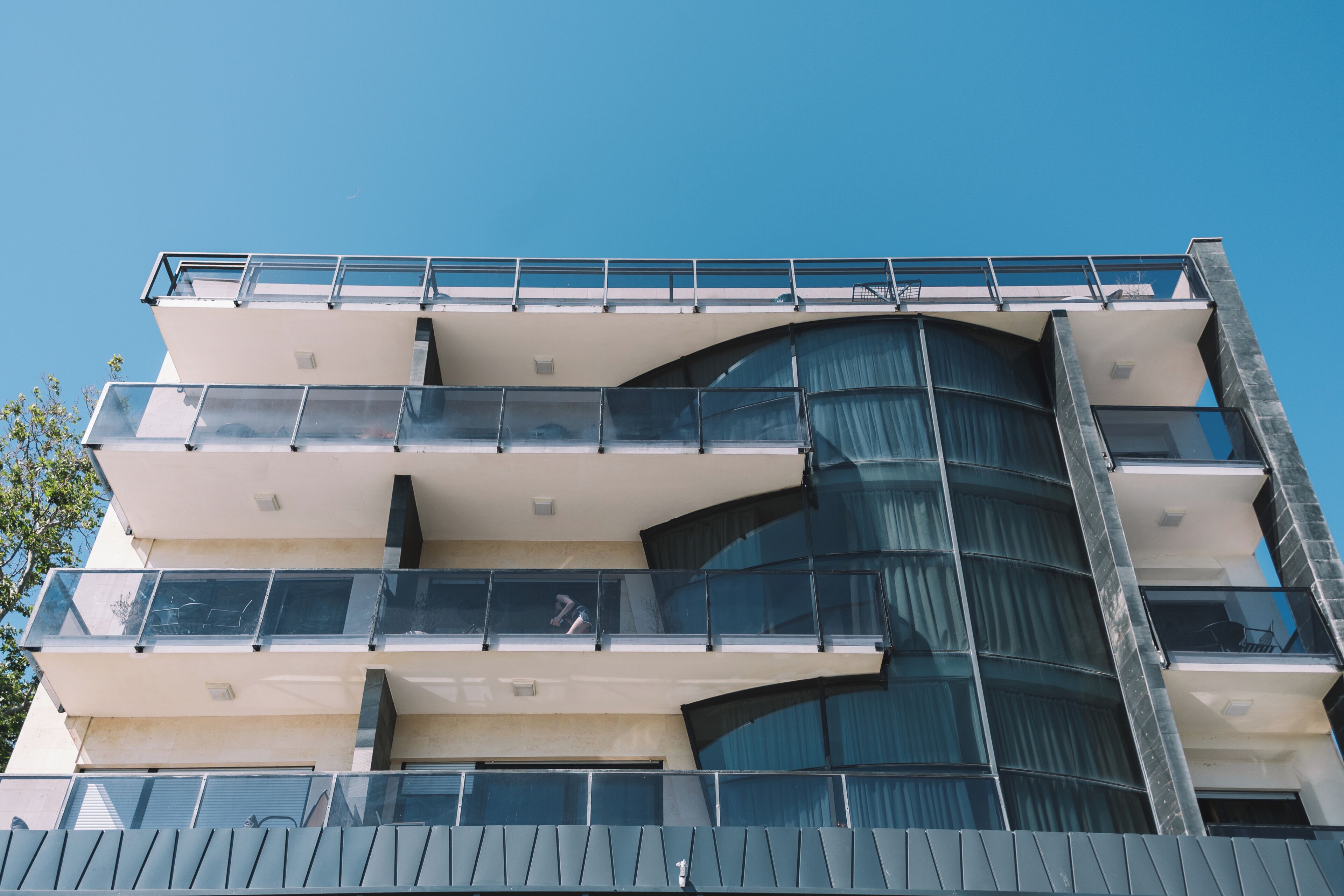 A multi-story building with balconies, large windows, and a curved facade.