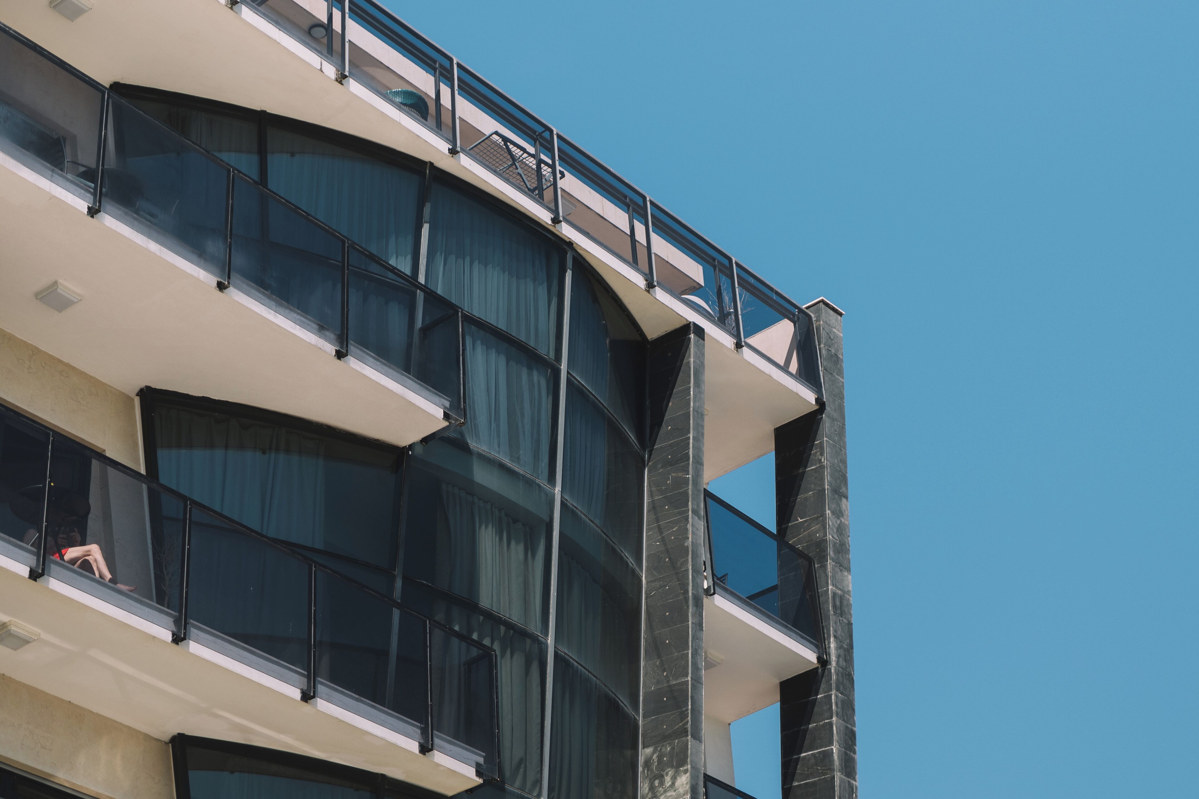A multi-story building with balconies, large windows, and a clear sky.