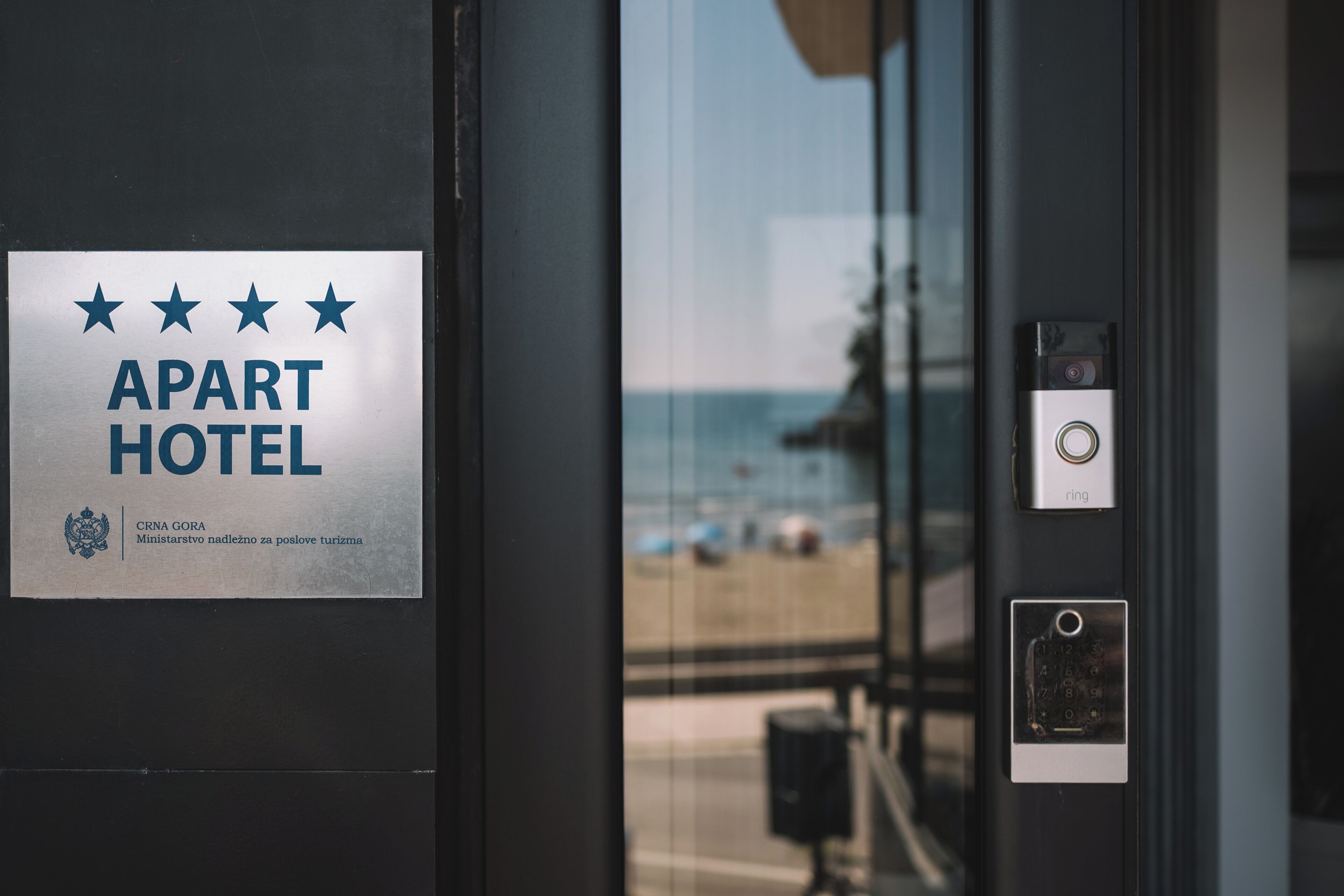 Une enseigne d’hôtel indiquant un classement cinq étoiles, une vue sur la plage depuis la fenêtre et une porte dotée d’un clavier numérique et d’une serrure.